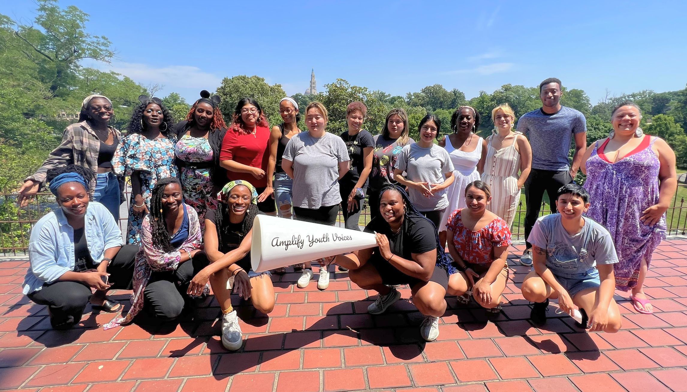 Large group of youth authors who wrote the Mini Mirrors book series and their story coaches, with one author holding a giant megaphone with the words “Amplify Youth Voices” on the side.