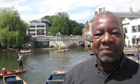 Color photograph of poet Tyrone Williams with a background scene of boats and a canal