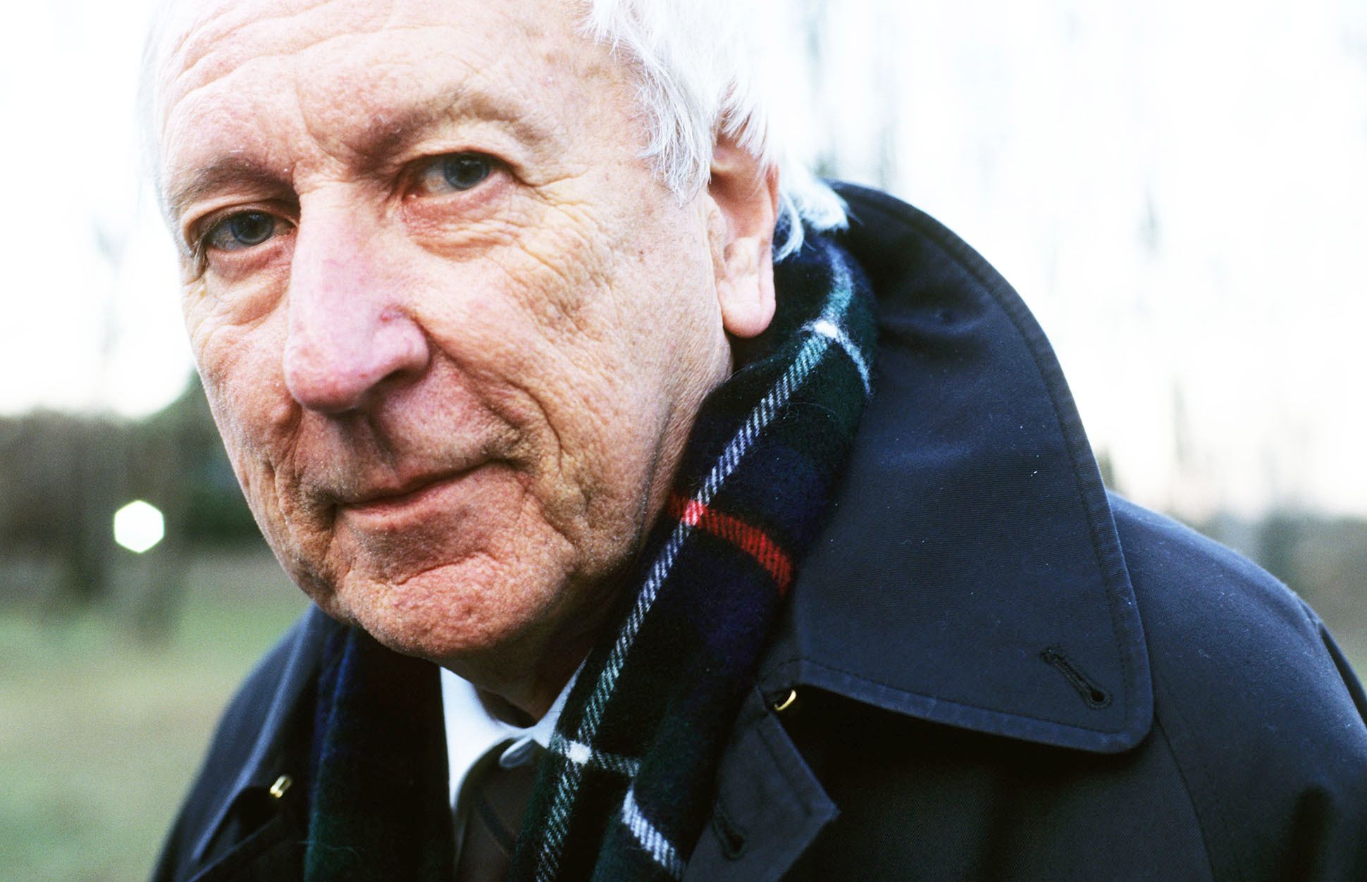 Headshot of Tomas Tranströmer wearing a dark blue coat and plaid scarf