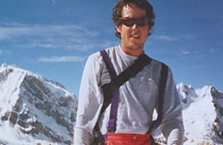 Poet Ethan Stebbins in red sunglasses, standing in front of snowy mountains.