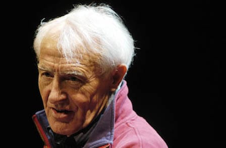Headshot of poet Jon Stallworthy in a red jacket.