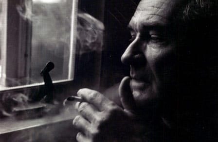 Black and white side profile of poet and translator Robert Fitzgerald smoking by a window.