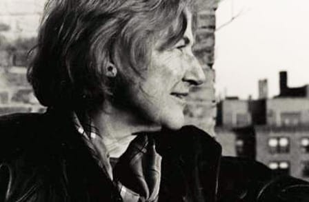 Side headshot of poet Mary Ann Caws outside on a balcony.