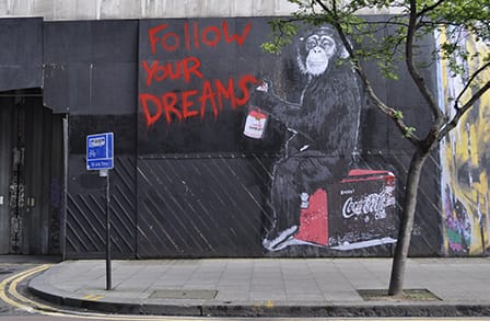 Image of ale's street art, "Follow Your Dreams" with a chimp spray painting