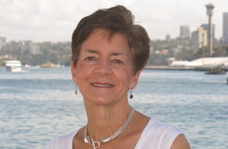 Headshot of Sue Ellen Thompson across  the water from a city skyline.