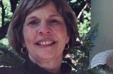 Headshot of poet Jeanne Murray Walker in front of green plants.
