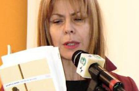 Color photograph of Italian poet Antonella Anedda reading in front of a mic