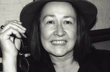 Black and white headshot of poet Dara Wier wearing a hat.