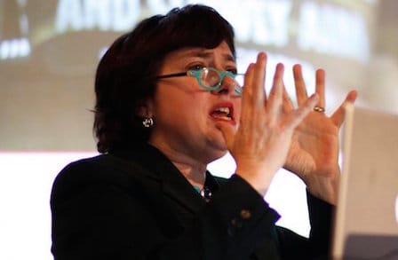 Poet Clare Cavanaugh gesturing with her hands as she speaks.