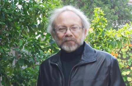 Headshot of poet David St. John in a leather jacket, outdoors.