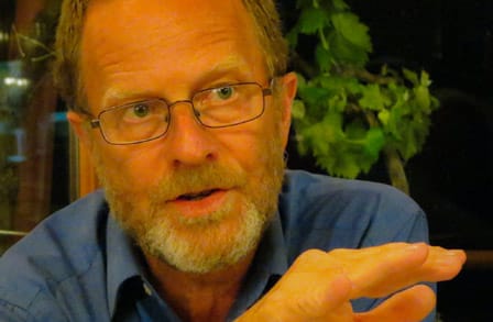 Headshot of poet David Mason, gesturing with his hand.