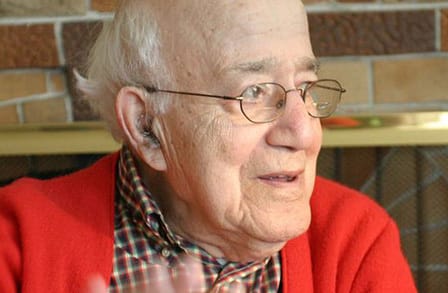 Headshot of poet Carl Rakosi in a red cardigan.