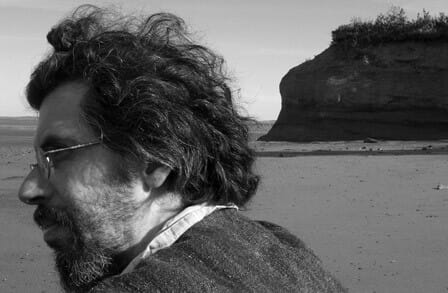 Black and white photograph of poet Edwin Torres facing the ocean