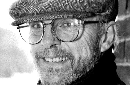 Black and white headshot of poet John Engels in a newsboy cap.