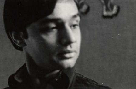 Cropped black-and-white portrait of Agha Shahid Ali, head turned and looking downwards.