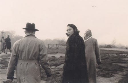 Archival image of Clarice Lespector walking in a group, looking back at the camera.