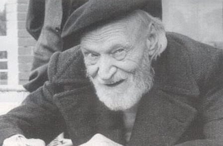 Black and white headshot of poet Giuseppe Ungaretti in a coat and cap.