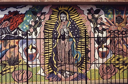 Photo of a Virgin Mary mural behind an iron fence