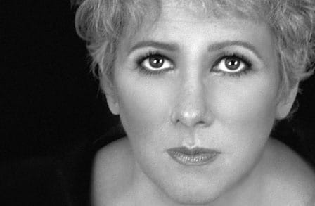Black and white headshot of poet Lynn Emanuel, looking up.