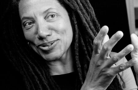 Poet Nikky Finney smiling, hands reaching out in front of her.