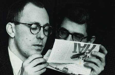 Paul Caroll reading a pamphlet with another man.