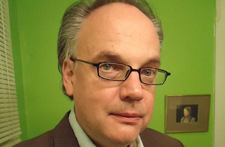 Headshot of writer  MD Hudson in front of a bright green wall.