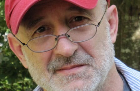 Headshot of poet David Bottoms in a red hat.