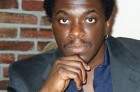 Headshot of writer Reginald O'Hare Gibson, with a hand to his chin.