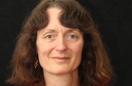 Headshot of writer April Ossmann in front of a black background.