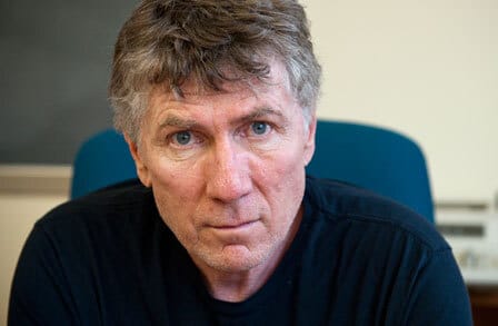 Headshot of poet James Galvin. in a blue chair..