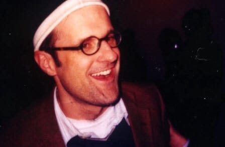 Headshot of writer Peter O'Leary wearing a white headband, with his mouth open.