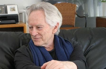 Michael McClure on a couch wearing a blue scarf.