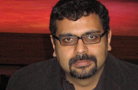 Headshot of writer Raa Ali Hasan, in front of a red sunset.
