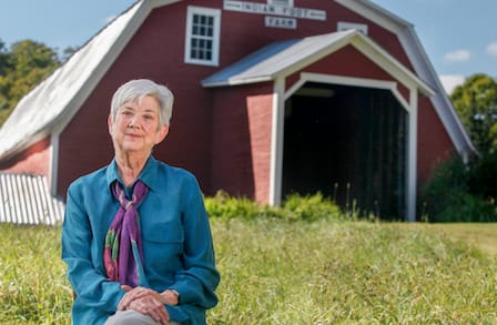 Poet Ellen Bryant Voigt in front of a red barn.