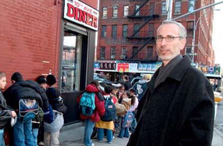 Writer Douglas Florian in a black overcoat k in front of a line outside a diner.