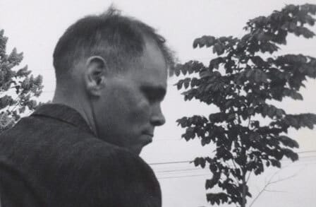 Black-and-white portrait of Larry Eigner outdoors, with his back turned to the camera.