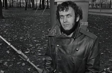 Poet Peter Cooley outdoors surrounded by leaves.
