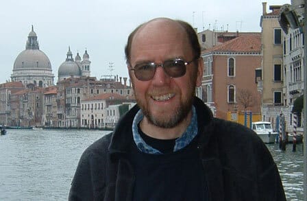 Poet Clive Wilmer in front of a city waterline.