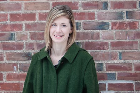 Poet Danielle Chapman standing in front of a brick wall.