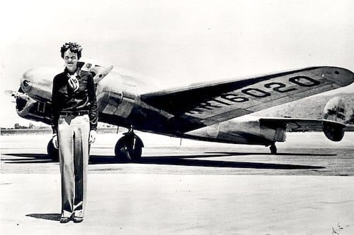 Amelia Earhart standing in front of her airplane