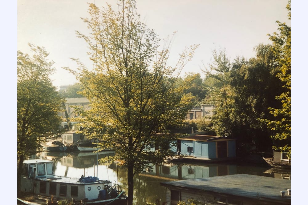 Photo fo a river and white houseboat, trees in spring