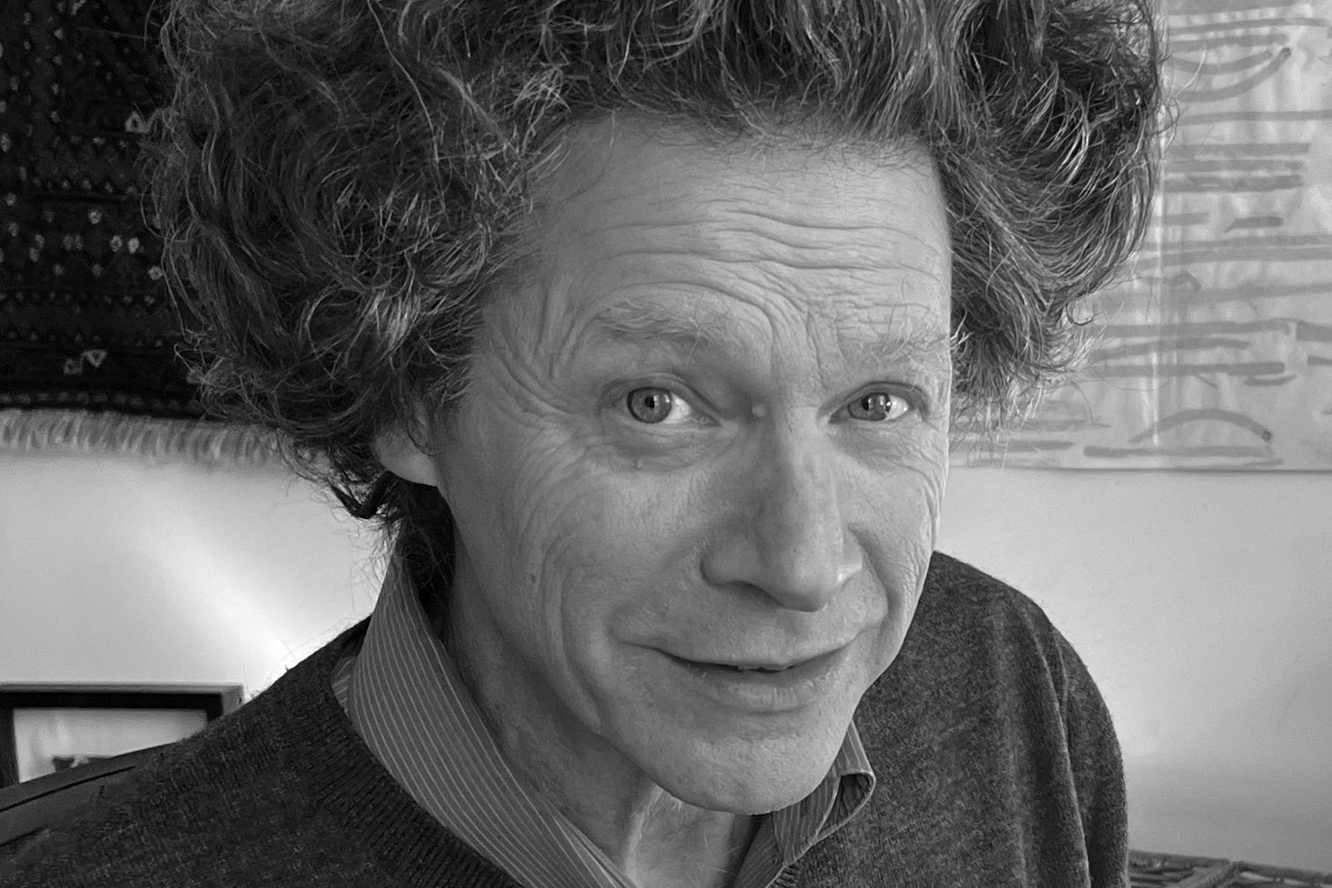 Black and white portrait of a man with big curly hair looking at the camera