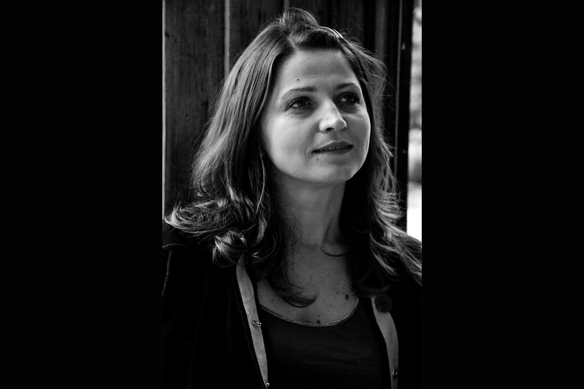 Albanian poet Luljeta Lleshanaku poses reflectively by a window. Black and white.