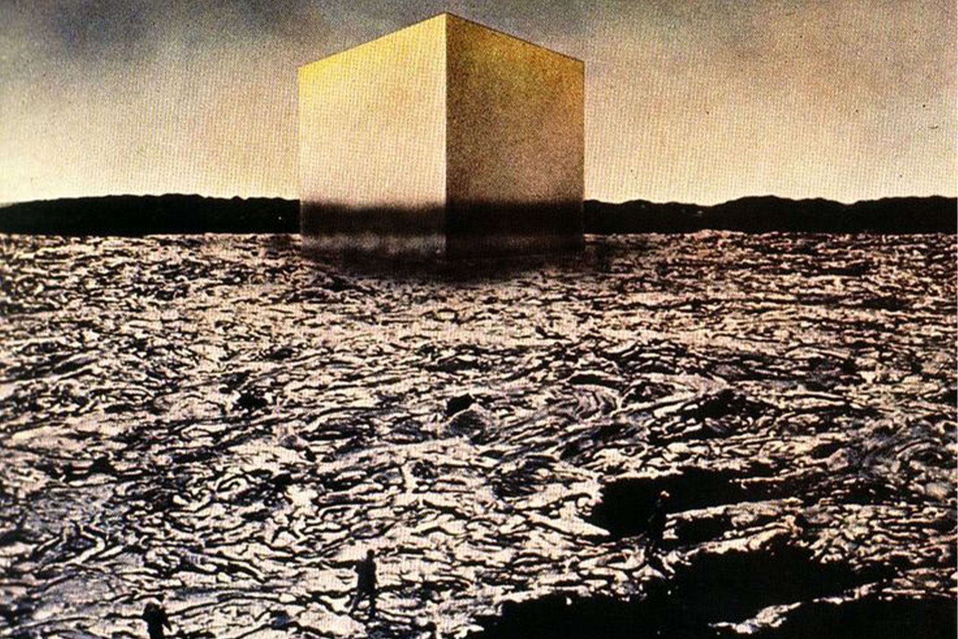 A photomontage in which a large gold cube looms over a field of rubble.
