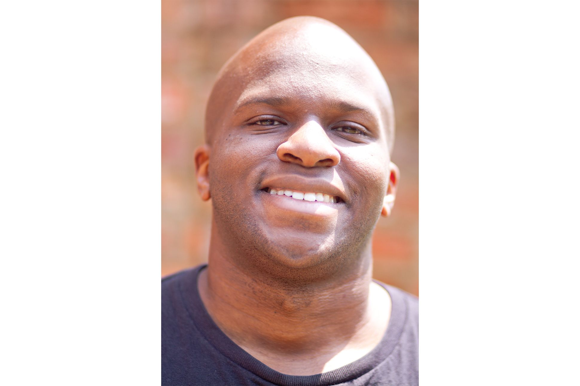 A black man with a black t-shirt smiling