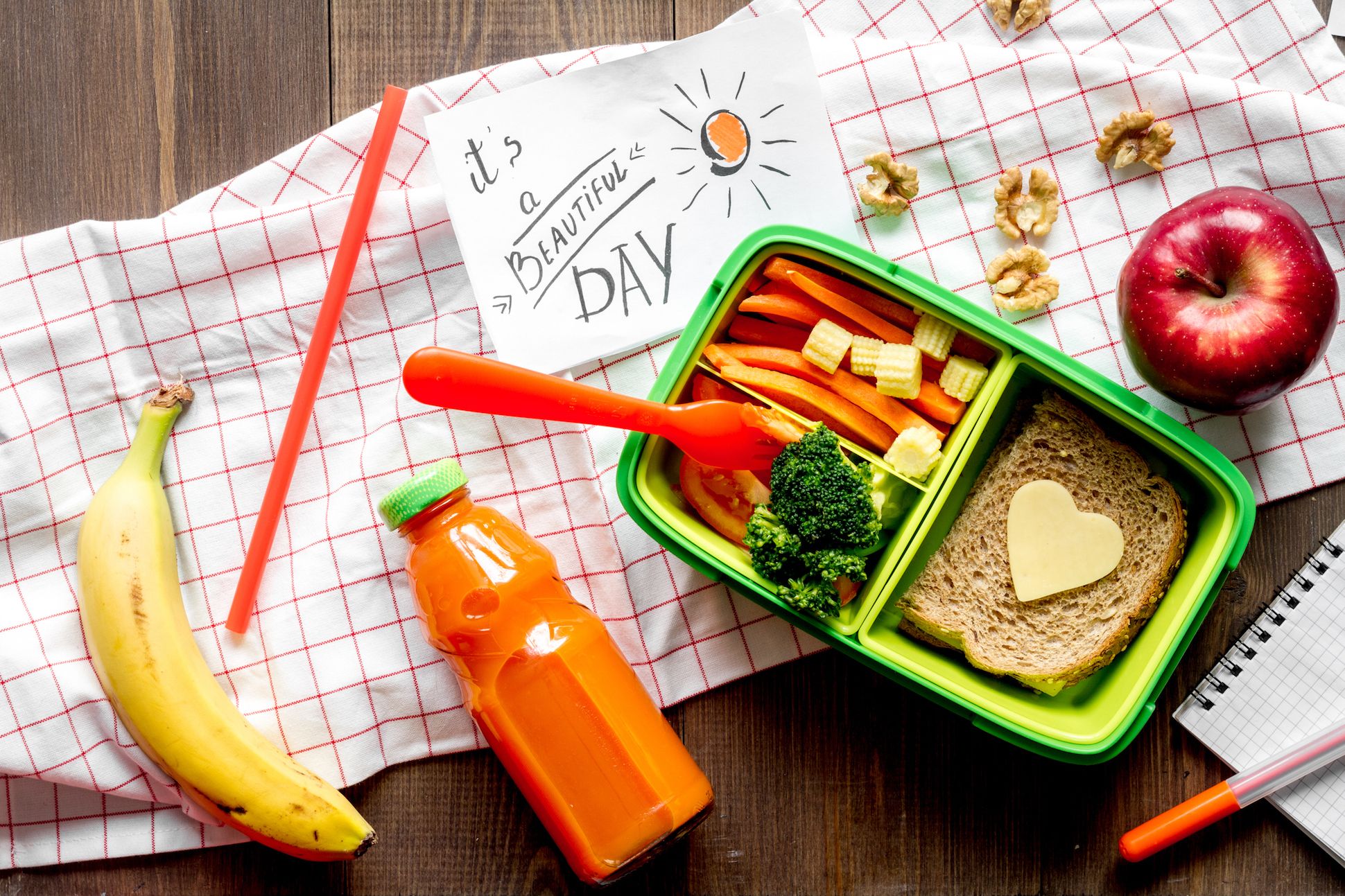 Image of a lunchbox with assorted food and snacks on a wooden table.