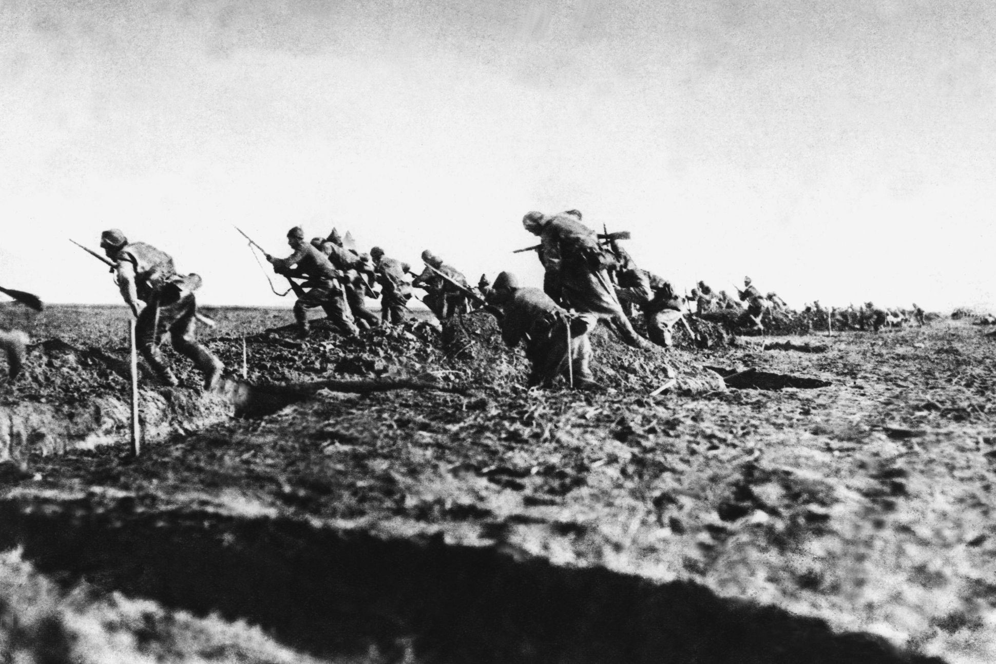 Image of soldiers running over trenches