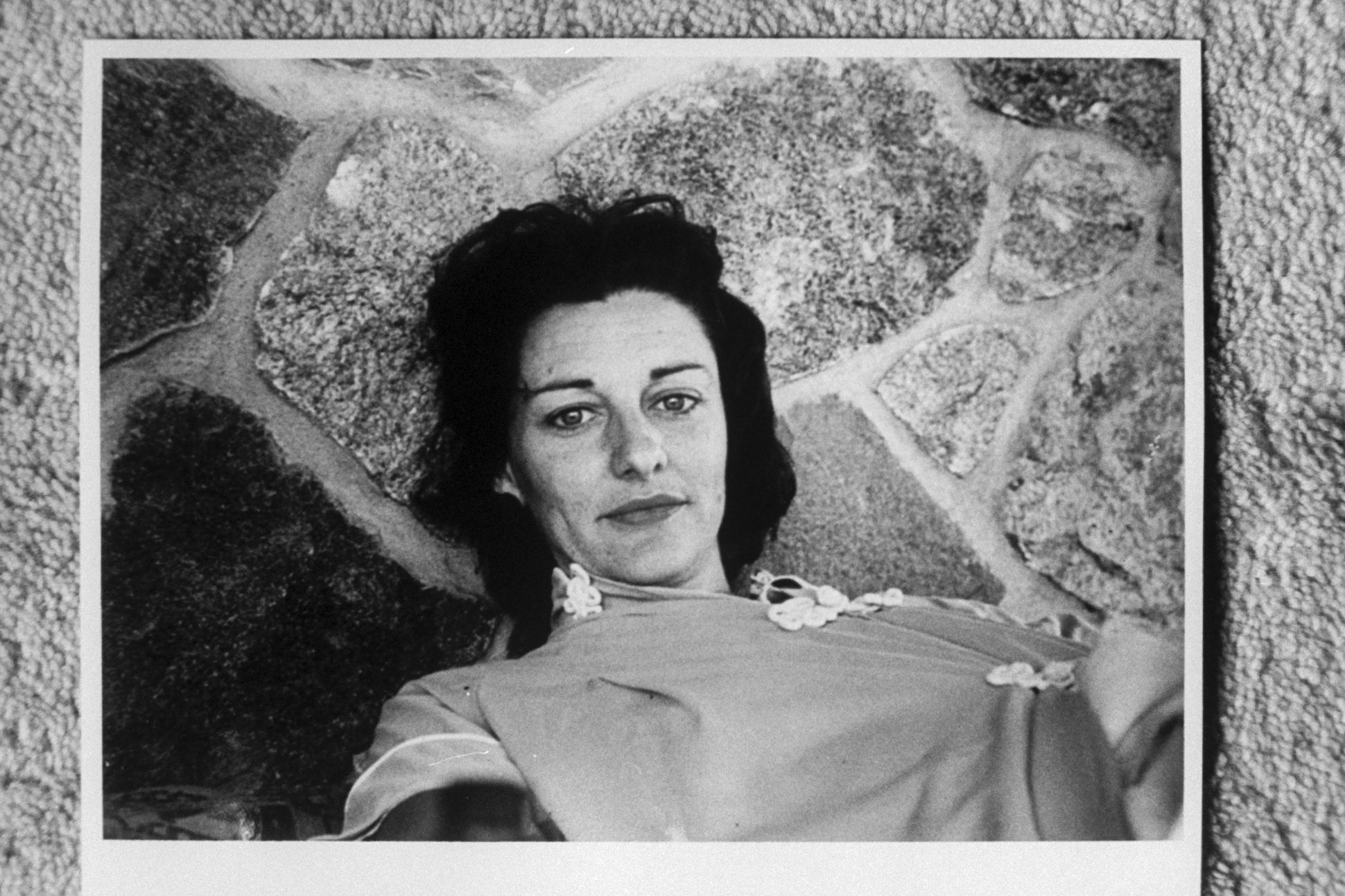 Poet Anne Sexton lying on stone patio.
