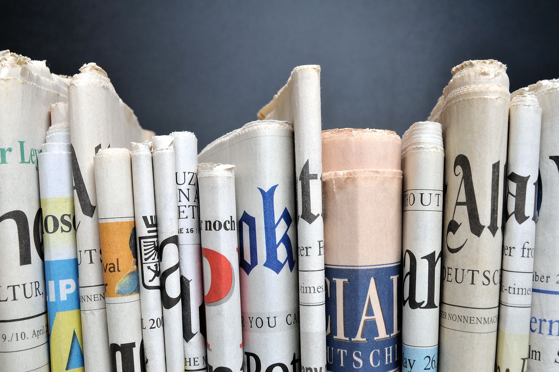 Image of folded newspapers in front of black wall.
