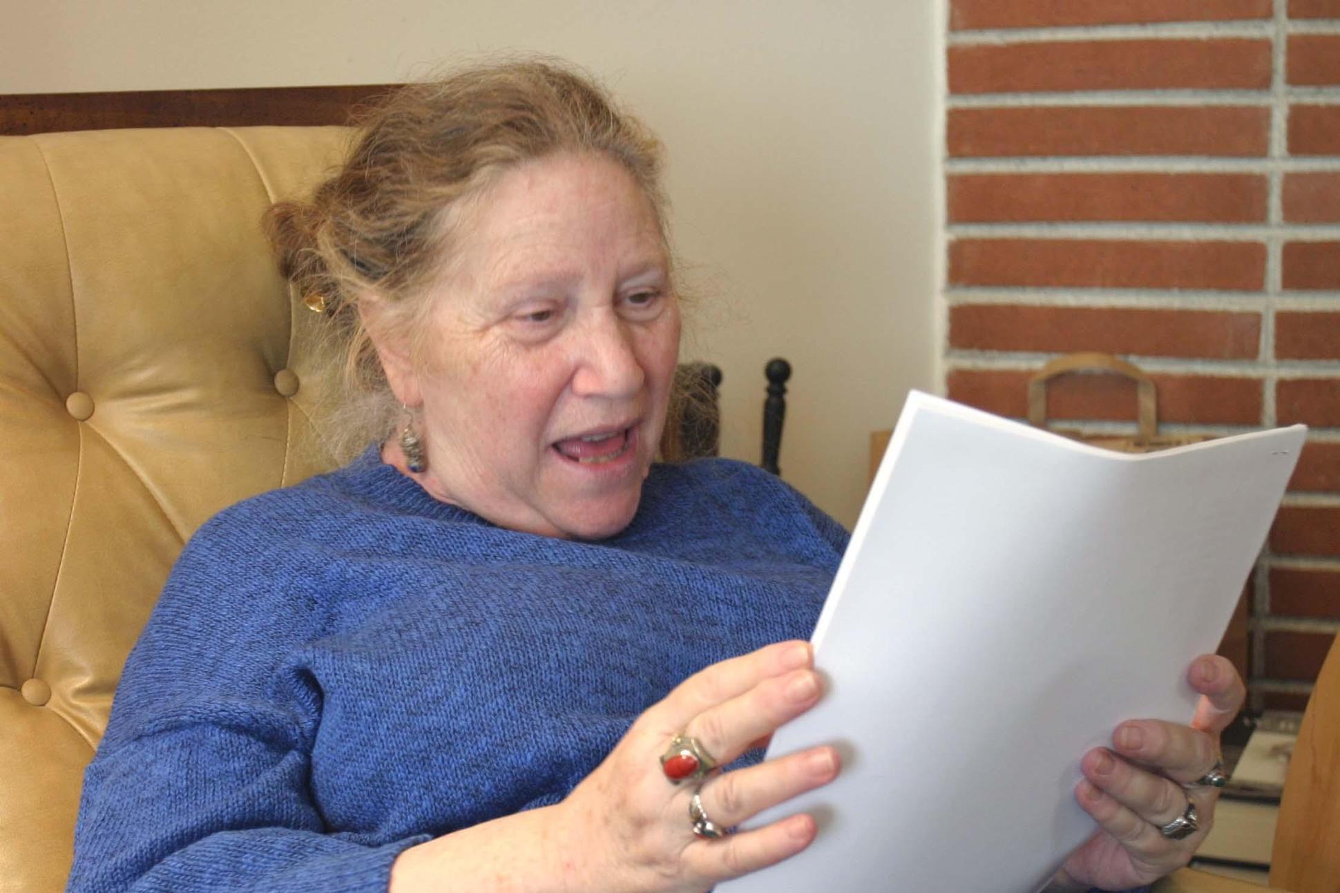 Poet Gloria Graham holding what looks like a manuscript of poetry